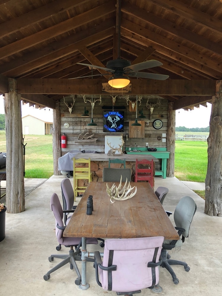 party pavilion with dining, fireplace, and firepit at oak creek ranch hunting lodge in columbus, tx